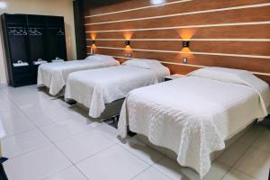 three beds in a room with white blankets at Hostal Face in La Paz