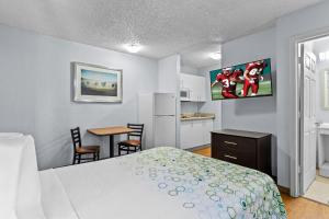 a bedroom with a bed and a table with chairs at HomeTowne Studios by Red Roof Orlando South in Orlando