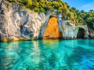 an arch in the rocks in the water at Natsios Apartments in Vlachopoulátika