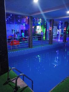 a swimming pool at night with people in a restaurant at OUR HILLs HOTELs AND SUITES in Ekoro