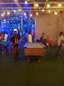 a man standing in a room with a pool table at OUR HILLs HOTELs AND SUITES in Ekoro