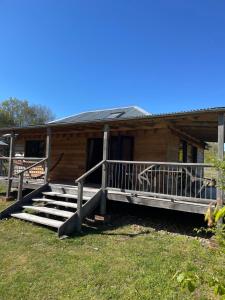 a wooden house with a porch and stairs in front of it at Zambezi Cabin in Halesworth