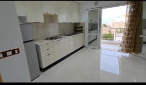 a kitchen with white cabinets and a large sliding glass door at Appartamento spazioso e luminoso in Mahdia