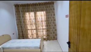 a bedroom with a bed and a window with curtains at Appartamento spazioso e luminoso in Mahdia