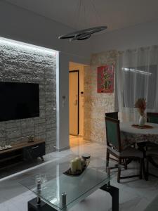 a living room with a television and a glass table at Aphrodite Apartment in Athens