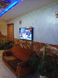 a living room with a couch and a tv on a wall at OUR HILLs HOTELs AND SUITES in Ekoro