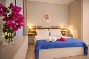 a bedroom with a bed with a vase of pink flowers at Nikoletta 5 in Vlachopoulátika