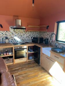 a kitchen with a stove top oven next to a couch at Zambezi Cabin in Halesworth +4 photos