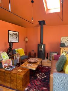 a living room with orange walls and a wood stove at Zambezi Cabin in Halesworth