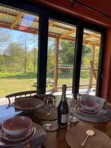 a table with glasses and a bottle of wine at Zambezi Cabin in Halesworth