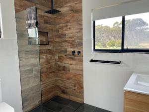a bathroom with a shower with a glass door at Stokes Bay Cliffs Kangaroo Island in Stokes Bay +57 photos