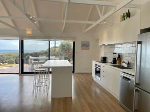 a kitchen with white cabinets and a table with chairs at Stokes Bay Cliffs Kangaroo Island in Stokes Bay