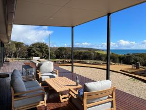 a patio with chairs and a table and a view of the ocean at Stokes Bay Cliffs Kangaroo Island in Stokes Bay