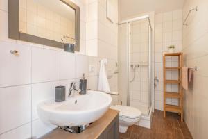 a white bathroom with a sink and a toilet at FeWo Dünengrün in Trassenheide