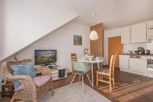 a living room with a table and chairs and a kitchen at FeWo Dünengrün in Trassenheide +17 photos