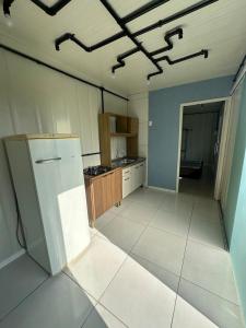 an empty kitchen with a refrigerator in a room at Casa Container Completa e Privativa em Sombrio-SC in Sombrio