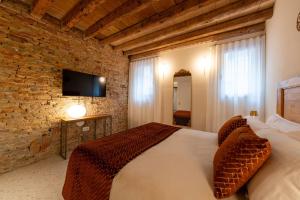 a bedroom with a bed and a brick wall at Spaccavento Boutique Rooms in Chioggia