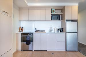 a kitchen with white cabinets and stainless steel appliances at Waves & Wellness - Spa Pool and Parking in Christchurch