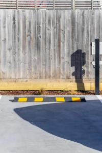 a shadow of a fence and a parking meter at Waves & Wellness - Spa Pool and Parking in Christchurch