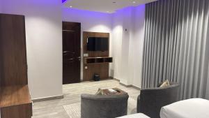 a hotel room with two chairs and a television at شقق زهرة النزلاء المخدومة الخرج in Al Kharj
