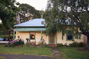a small white house with a bench in the yard at Tarndwarncoort Homestead in Warncoort