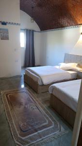 a bedroom with two beds and a rug at Kenzy House Abu Simbel in Abu Simbel