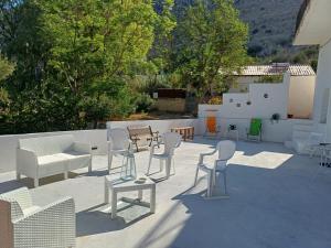 a patio with white chairs and tables and chairs at Oikos Terrasini in Terrasini