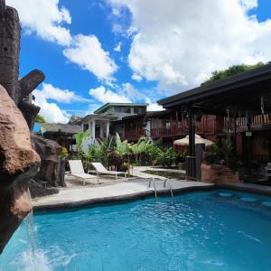 a swimming pool in a resort with a waterfall at Poshtel Arenal in Fortuna