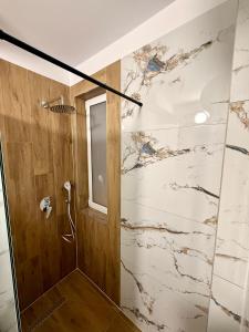 a bathroom with a shower with a marble wall at Aisha Apartment in Berat +47 photos