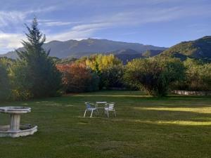 two chairs and a table in a field with mountains at Loft Las Acacias in Potrero de los Funes