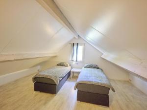 a attic room with two beds and a window at Scheldeoord 54 in Baarland +32 photos