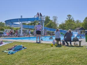 a group of people sitting in the grass near a swimming pool at Scheldeoord 54 in Baarland