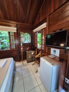 a living room with a television and a small refrigerator at Aratinga Inn in Abraão