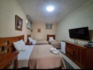 a hotel room with two beds and a flat screen tv at Maximos Petit Hotel in Flores +4 photos