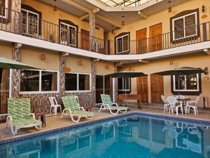 a pool with chairs and umbrellas next to a building at Maximos Petit Hotel in Flores