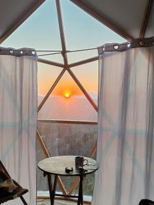 a room with a table and a window with the sunset at Glamping Entre las Nubes in Mineral del Monte