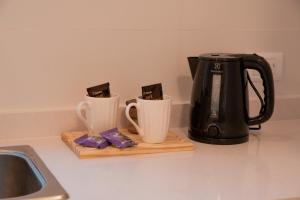 a coffee maker and two cups on a kitchen counter at Epoca in Tandil