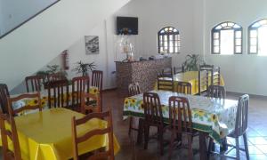 a dining room with yellow and white tables and chairs at Pousada Gira-Sol in São Pedro da Aldeia