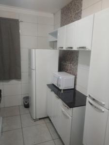 a kitchen with a white refrigerator and a microwave at Ap Simples arc, bem localizado confortável e aconchegante, 2 quartos in Araçatuba