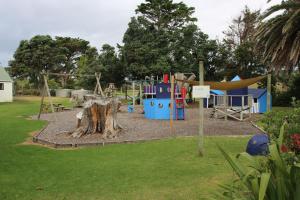 a playground in a park with a slide and swings at Pakiri Beach Holiday Park in Pakiri