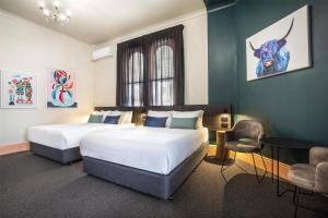 a hotel room with two beds and a chair at Ramsgate Hotel by Nightcap Social in Adelaide
