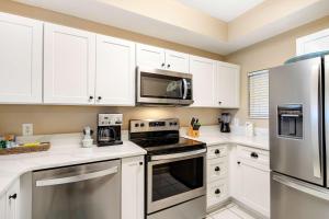 a kitchen with white cabinets and stainless steel appliances at Beachside Resort Condo with Pools and Tennis in Destin