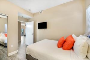 a bedroom with a bed with orange pillows and a tv at Beachside Resort Condo with Pools and Tennis in Destin