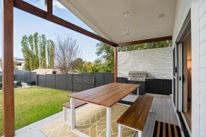 a patio with a wooden table and a grill at Lakeshore Serenity @ Warners Bay in Warners Bay