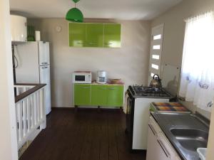 a kitchen with green cabinets and a white refrigerator at Desiderata in Punta Del Diablo +26 photos