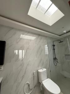 a white bathroom with a toilet and a skylight at Adi Villa in Darmasaba +18 photos