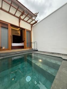 a house with a swimming pool and a bedroom at Adi Villa in Darmasaba