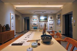 ein Esszimmer mit einem langen Tisch und einigen Bildern an der Wand in der Unterkunft Interlude Inn, Boutique Art Retreat, Cultural Experience, Artisan Breakfast in Fenghuang