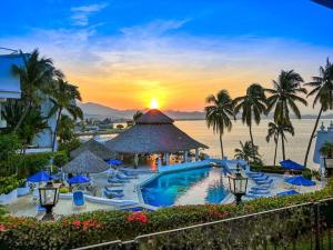 a resort with a pool and palm trees and a sunset at PlayaSol las Hadas in Manzanillo