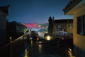 Ein Tisch und Stühle auf einem Balkon bei Nacht in der Unterkunft Interlude Inn, Boutique Art Retreat, Cultural Experience, Artisan Breakfast in Fenghuang